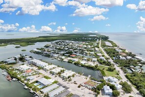 An aerial view of a coastal residential area with houses, docks, and a marina.