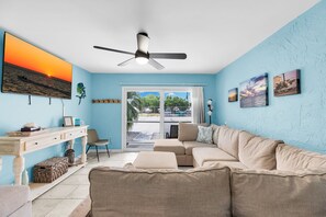 A living room with a sofa, a desk, and a ceiling fan.