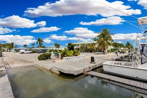 A marina with a docked boat, a parking area, and a building with a green roof.