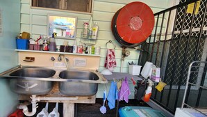 A kitchen with two stainless steel sinks, a mirror, and various kitchen items on shelves. - Meyenburg Unit 5, 2 Double Bed's 4 Pax (Mount Morgan)