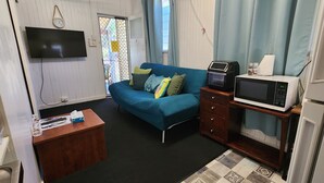 A compact room with a sofa, a small desk, a microwave, and a refrigerator. - Meyenburg Unit 5, 2 Double Bed's 4 Pax (Mount Morgan)