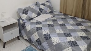 Ein Schlafzimmer mit einem Bett, einem Nachttisch, einem blauen Teppich und drei Wandbildern.
