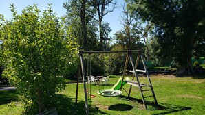 A swing set, a bench, and a small pond in a grassy park area.