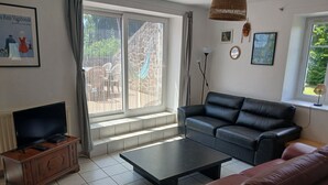 A living room with a sofa, a coffee table, a TV, and a window with curtains.