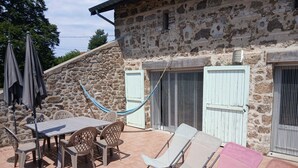 A patio with a table and chairs, a hammock, and lounge chairs.