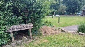 A wooden sign with text, a grassy area, a swing set, and a pile of hay.