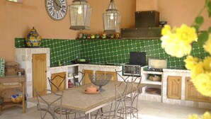 A kitchen with a green tiled backsplash, a stove, a microwave, and a dining table with chairs. - ABSOLUTE QUIET 45 km from the sea (St-Maxime St-Tropez). (Lorgues)