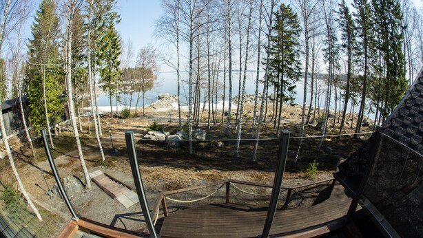 A wooden deck with a view of a lake and trees. - Seaside Villa with jacuzzi and own beach (Maksamaa (Vöyri))