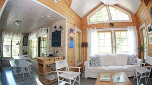A cozy wooden cabin interior with a dining area, a sofa, and a coffee table. - Seaside Villa with jacuzzi and own beach (Maksamaa (Vöyri))