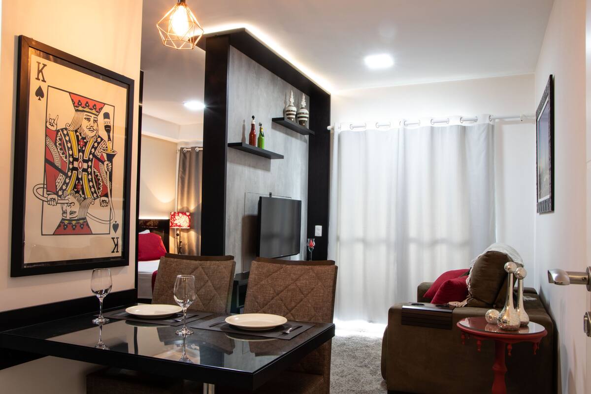 Un coin repas avec une table en verre, des chaises et une carte à jouer encadrée accrochée au mur.