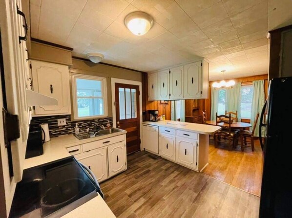 A compact kitchen with a central island, wooden flooring, and white cabinetry.