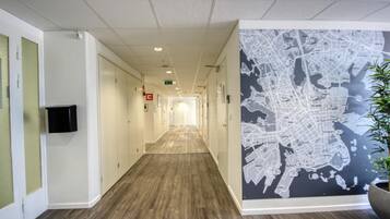 A long, narrow hallway with wooden flooring, white walls, and a large map mural on one side.