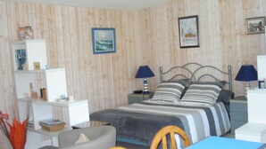 Un dormitorio con una cama, dos mesitas de noche con lámparas, una silla, un escritorio y una estantería con diversos objetos.