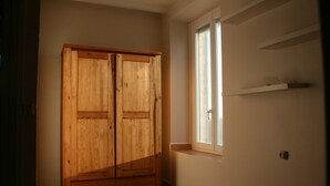 Una habitación con un armario de madera, ventana con vistas y suelo de baldosas.