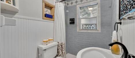 Et badeværelse med toilet, håndvask og bruser.