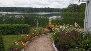 A gravel pathway leading to a white building with a view of a lake and a power line tower in the background. - Lakefront  Fall Foliage in New England Just 2 Hours From NYC (Sharon)