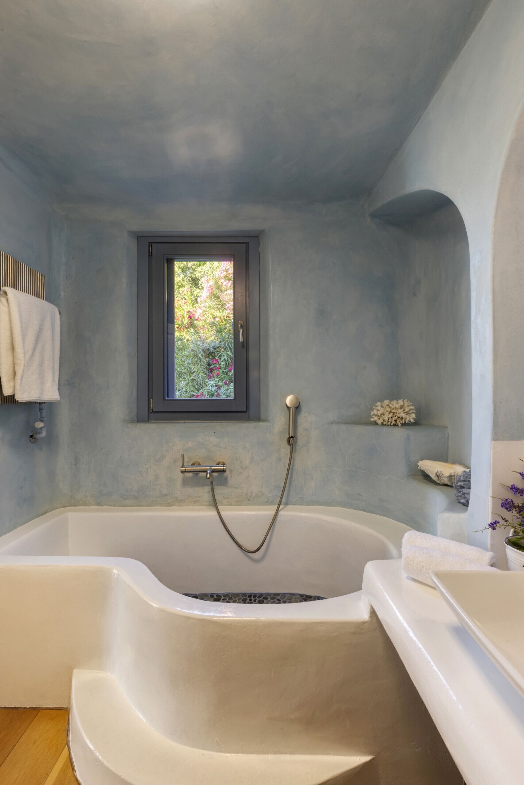 Un baño con una bañera grande, una ventana y un perchero para toallas.