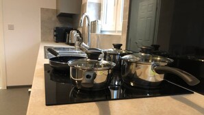 A kitchen with a black stovetop, stainless steel pots, and a modern faucet. - ELD1 - Large 2 bedrooms, Complimentary Netflix & Parking (Peterborough)