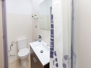 A modern bathroom with a white toilet, a white sink, and a glass shelf with a small plant. - Nice apartment for 5 guests with WIFI, A/C, TV and balcony (Barcelona)