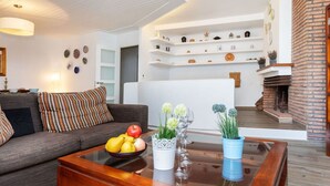 A modern living room with a sofa, coffee table, and decorative items. There is a fireplace and a staircase leading to an upper level. - Beautiful  villa for 5 guests with WIFI, TV and balcony (Tossa De Mar)