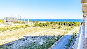 Vista de varanda com vista para a costa, incluindo uma área de construção, uma estrada e céu azul.