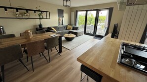 Ein modernes Wohnzimmer mit Essbereich, einer Couch, einem Couchtisch und einer Küche mit Herd.