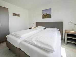 A double bed with white linens, a bedside table with a lamp, and a small picture on the wall. - Beautiful apartment in villa for 4 guests with WIFI, TV, terrace and pets allowed (Truppach)