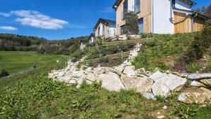 A modern house with a stone pathway leading to the entrance, surrounded by greenery and a clear blue sky. - Lovely apartment in villa for 8 people with WIFI, TV, terrace and pets allowed (Obernsees)