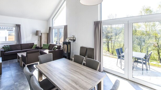 A spacious living area with a large table and chairs, a sofa, and a fireplace. - Lovely apartment in villa for 8 people with WIFI, TV, terrace and pets allowed (Obernsees)
