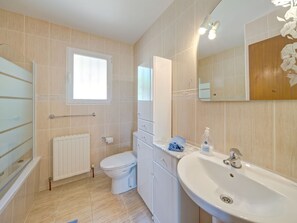 Bathroom features a toilet, sink with soap dispenser, and mirror.