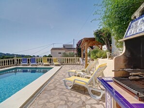 Relax by the pool with lounge chairs and a barbecue grill nearby.
