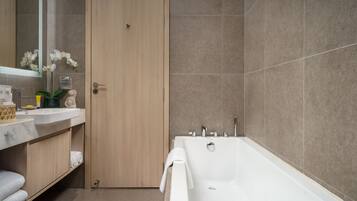 A modern bathroom with a bathtub, a wooden door, and a marble sink.