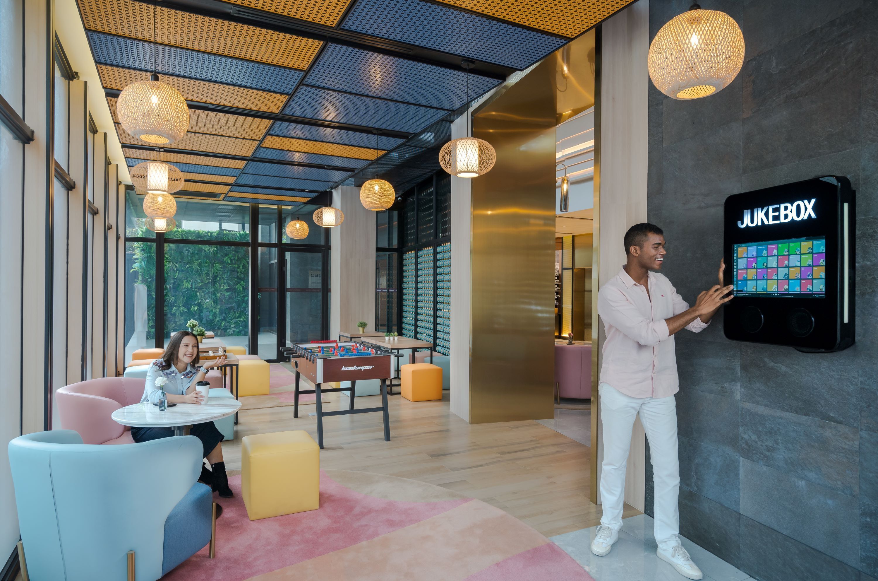 A modern interior with a foosball table, a jukebox, and a seating area with colorful chairs.