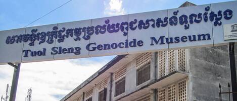 Señal del Museo Genocidio Tuol Sleng, con un cielo despejado al fondo.