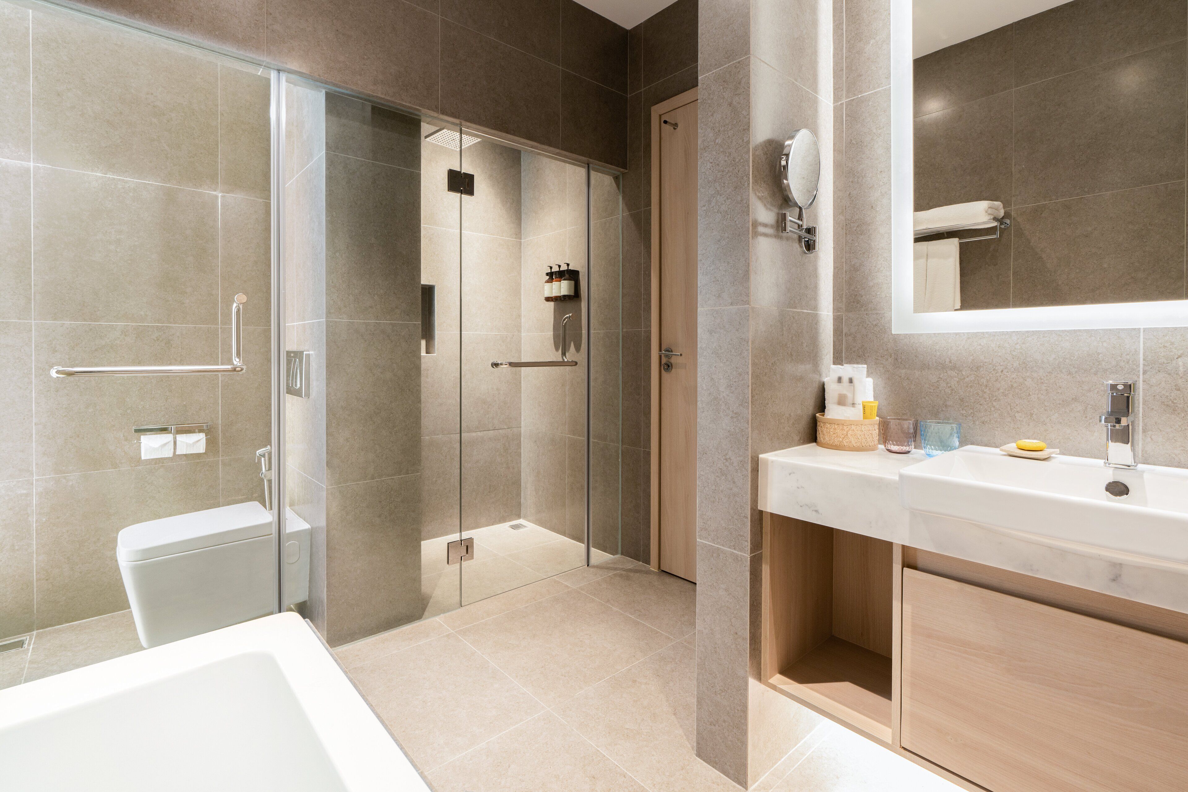 Ein modernes Badezimmer mit einer gläsernen Duschkabine, einer großzügigen Badewanne und einem Waschtisch mit Spiegel.