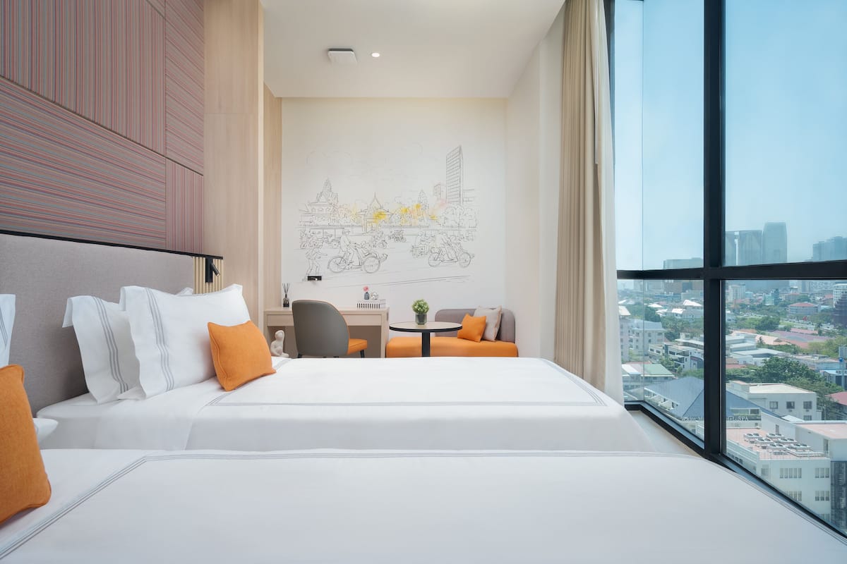 A modern hotel room with a large bed, a desk, and a view of the city.