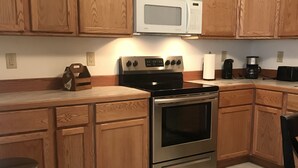 A kitchen with wooden cabinets, a stainless steel stove, a microwave, and a coffee maker.