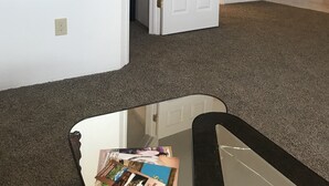 A hallway with a white door, a framed picture on the wall, and a carpeted floor.