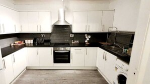 A modern kitchen with white cabinets, a black countertop, a stainless steel range hood, and a built-in oven. - Modern Apartment in Fantastic Location (Glasgow)