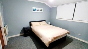 Una camera da letto con un letto, un comodino, un termosifone e una finestra.