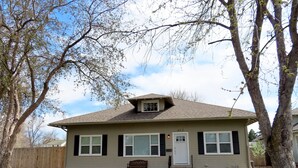 A single-story house with a gabled roof, a front porch with a bench, and a visible mailbox.
