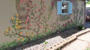 A building with a mural of flowers and a window with blue shutters.