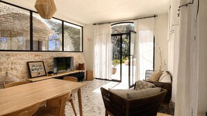 A dining area with a wooden table and chairs, a television, and a stone wall.