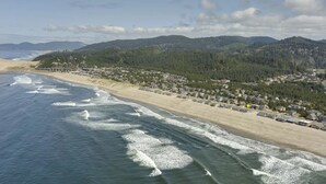 Ein Luftbild einer Küstenstadt mit Strand, Häusern und bewaldeten Hügeln.