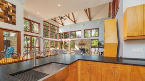 Een moderne keuken met houten kastjes, een zwart aanrecht en een groot raam.