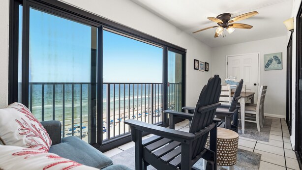 A balcony with a view of the beach, a ceiling fan, and a dining area with chairs and a table. - Beach Front, Balcony access from den and master, Spacious living, fully equipped (Gulf Shores)