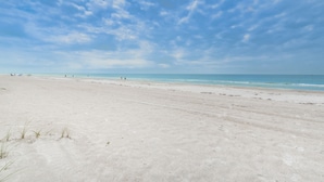A wide sandy beach with a clear sky and calm sea. - Direct Oceanfront Oasis: Remodeled Home with Private Heated Pool (Indian Shores)