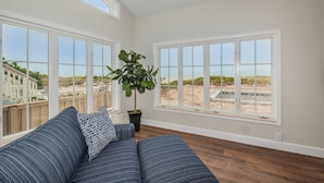 A spacious living room with large windows, a ceiling fan, and a potted plant. - Direct Oceanfront Oasis: Remodeled Home with Private Heated Pool (Indian Shores)