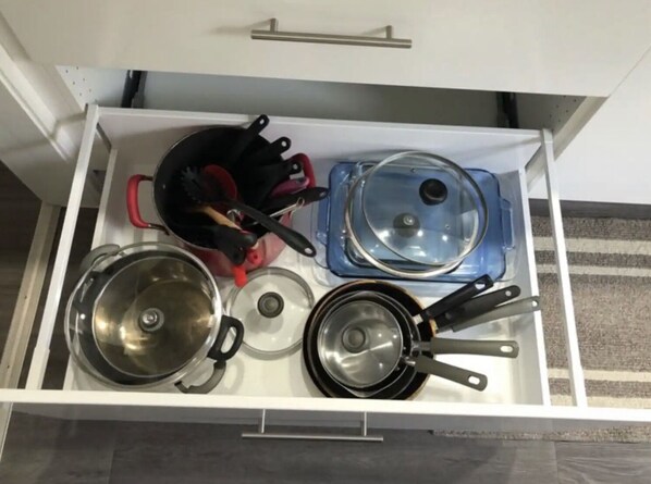 Un cajón de la cocina con diferentes ollas y sartenes.