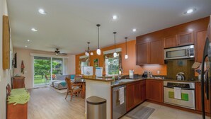A modern kitchen with wooden cabinets, stainless steel appliances, and a central island. - Paradise vibes awaits @ Hali"i Kai, ocean front resort in Waikoloa Beach (Waikoloa Village)
